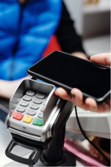 Hand holding a mobile phone over a payment reader