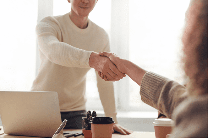 Two people shaking hands across a table